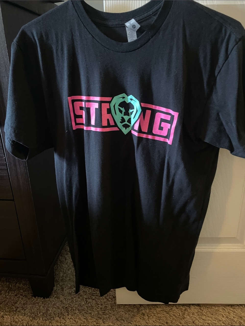 Unisex Next Level Apparel Black Tee with Pink STRONG Banner and Teal Crest